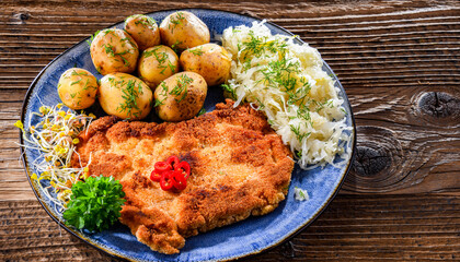 Pork cutlet coated with breadcrumbs with potatoes and cabbage