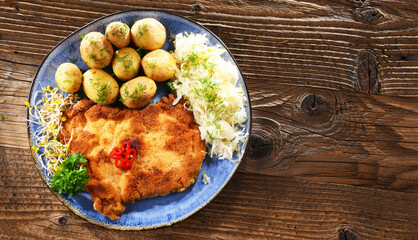 Pork cutlet coated with breadcrumbs with potatoes and cabbage