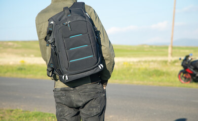 Man with backpack standing on the road.