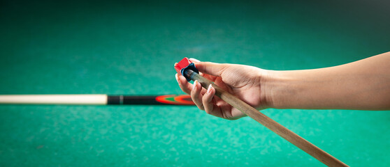 Caucasian woman chalking billiard cue.