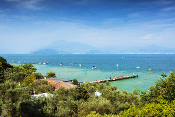 View on turquoise Garda lake in Sirmione over olive trees - 516137546