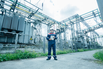 An energy engineer inspects the modern equipment of an electrical substation before commissioning....