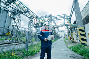 An energy engineer inspects the modern equipment of an electrical substation before commissioning....