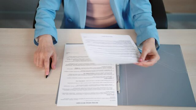 employee sitting at a desk opening folder reading signing contract