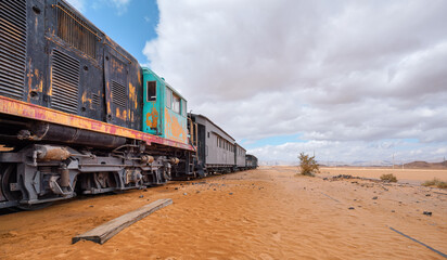 Old unused diesel locomotive and train at Wadi Rum railroad station, sandy desert around