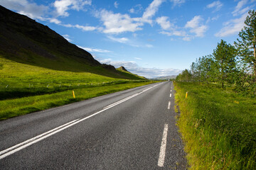 Fototapeta premium Very picturesque empty road in iceland in summer. Asphalt road as a symbol of freedom and travel.