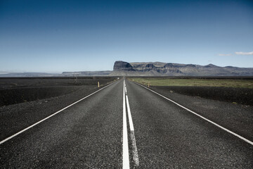 Fototapeta premium Very picturesque empty road in iceland in summer. Asphalt road as a symbol of freedom and travel.