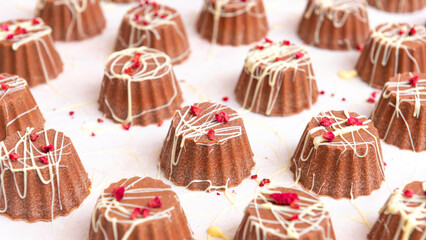 Chocolate candy cups with raspberry grains on white paper, with small part up. Close up image from above.