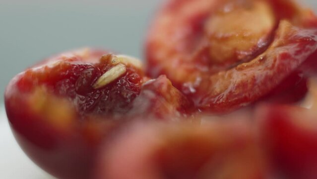 Two white worms crawl on the pulp of red sweet cherry, macro, close-up. Invertebrates, cherry fly larvae feed on berries, crawl inside the fruit. Wormy cherry.