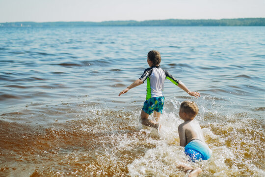 cute caucasian boys running into water with splashes and laughter. Vacatiom on sea side. Happy childhood. Image with selective focus