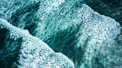Drone view over ocean waves , on summer sunny day. Top view to the beautiful green Atlantic Ocean. Aerial view:  Big sea waves with foam, closeup view.