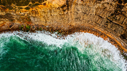 Top view to the beautiful  rocky sea shore. Drone view over ocean and rocky coastline shore, on summer sunny day. Aerial view: Ocean waves break on the rocky shore.