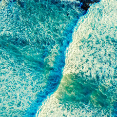 Beautiful  blue ocean waves - aerial view. Top view to the beautiful azure water sea surface.  Atlantic Ocean, Portugal. Drone view of rolling waves with white foam on the summer sunny day.