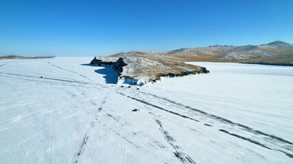 Fototapeta premium Frozen Lake Baikal from the air. Roads on the ice of the lake. Winter travel by car.