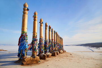 Wooden ritual pillars with multicolored ribbons on Cape Burkhan or Shamanka Rock. Lake Baikal in winter, Olkhon Island.
