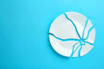 Pieces of broken ceramic plate on light blue background, flat lay. Space for text