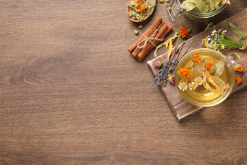 Fototapeta na wymiar Freshly brewed tea and dried herbs on wooden table, flat lay. Space for text