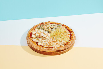 Italian pizza with four cheese on coloured background. Quattro formaggi pizza in minimal style on blue and orange color. American pizza delivery concept with color backdrop