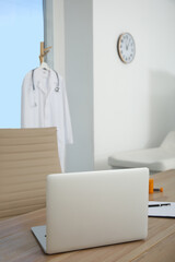 Modern laptop on wooden table in medical office. Interior design