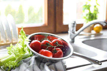 Fresh raw tomatoes and celery on countertop near sink in kitchen