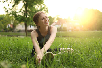 Naklejka na ściany i meble Teenage girl doing morning exercise on green grass in park