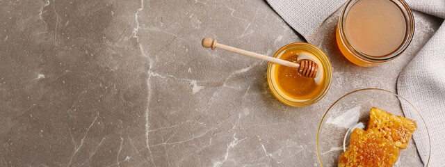 Tasty honey and combs on brown marble table, flat lay with space for text. Banner design