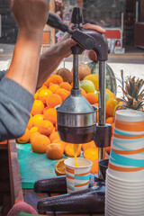 Seller squeezes juice from fresh oranges with a manual press. Street trading