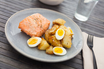 baked salmon fillet with fried potato wedges and quail eggs halves