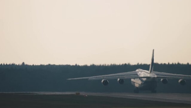 Silhouette of heavy cargo four-engine aircraft flies away, rear view. Soviet heavy long-range transport aircraft