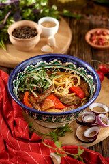 Eastern food - soup shourpa with vegetables and lamb meat on wooden table. Traditional uzbek soup with lamb meat, sweet pepper, tomatoes in rustic style. Caucasian cuisine on dark wooden background.