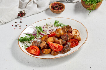 Traditional georgian dish odjahuri with meat and potatoes. Roasted pork fillet and potatoes with onion and tomatoes. Stew meat and potatoes. Eastern food with pork and spices