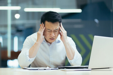 Upset and unhappy asian businessman reading documents and letter from bank, businessman at work in office disappointed with work result