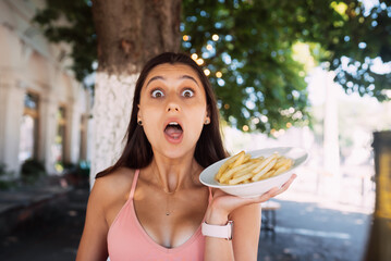 Young women hold french fries on white plates. Street cafe - 516152970