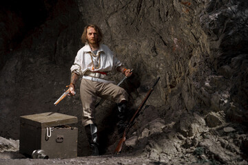 Sea robber captain of pirate ship armed with treasure chest in cave. Concept historical halloween....