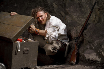 Sea robber captain of pirate ship armed with treasure chest in cave. Concept historical halloween....