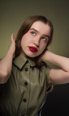 Portrait of a young attractive girl with expressive red lips and long smooth hair of a light shade in a stylish green dress . Close-up, green background