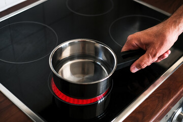 an adult man puts a ladle of water on the stove to cook spaghetti