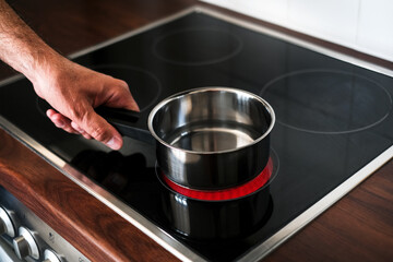 an adult man puts a ladle of water on the stove to cook spaghetti