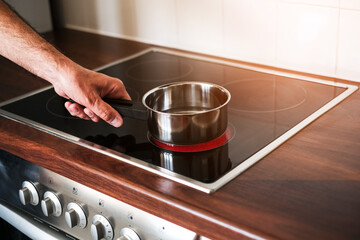 an adult man puts a ladle of water on the stove to cook spaghetti
