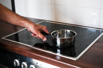 an adult man puts a ladle of water on the stove to cook spaghetti