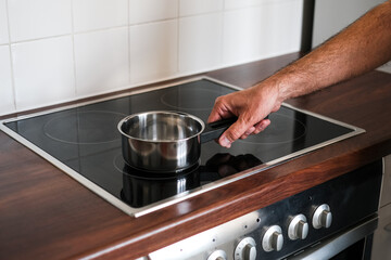 an adult man puts a ladle of water on the stove to cook spaghetti