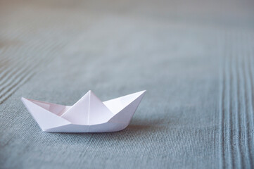 White paper boat on a light blue fabric background 