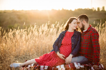 Romantic picnic outside the city in an autumn meadow under the sunlight. Pregnant mother-to-be...