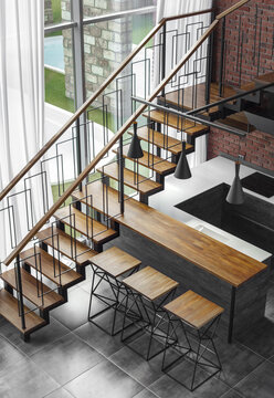 Modern loft kitchen interior with panoramic window and wooden staircase to the second floor.. High quality photo