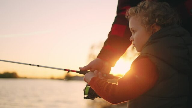 little boy is spending weekend with dad or grandpa in nature, child is fishing by rod