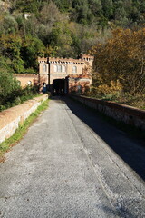 Fototapeta na wymiar Bridge and building at the entrance to the park of Villa Fabbricotti in Carrara, Tuscany, Italy