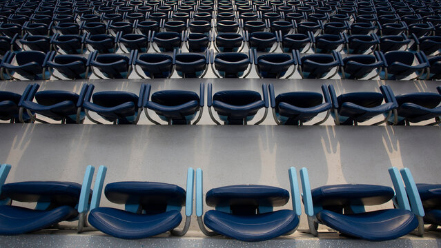 A photo of the blue stands at the stadium, a specially blurred picture for the background, a beautiful sun glare at the end of the seats, a huge cinema with chairs, a lot of empty seats, deserted