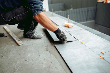 Professional tiler and ceramic tiles worker on construction site. hands of the tiler are laying the...