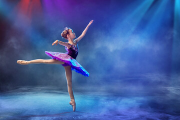 A little Japanese ballerina dances on stage in a lilac tutu on pointe shoes classical ballet.