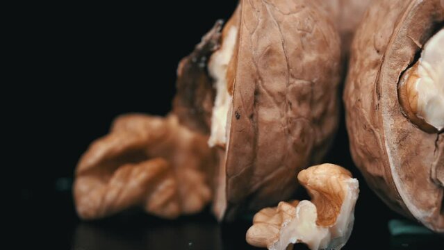 Lot of walnuts in the shell are spinning on a black background. Nuts are good for the brain. Heap of walnuts close-up.
